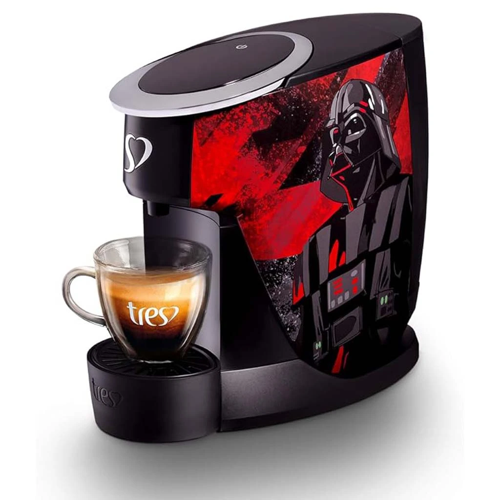 Trata-se de uma imagem que contém a cafeteira de cápsulas Star Wars da marca Três Corações de cor preta com vermelha e uma estampa lateral do darth Vader e fundo branco. Nessa cafeteira, há uma xícara contendo café. Uma das Melhores Cafeteiras de Cápsulas em 2024