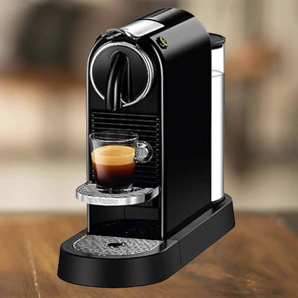 A imagem é composta pela cafeteira de cápsulas Nespresso Citiz de cor preta com uma xícara de café com bebida dentro. A cafeteira está sobre uma mesa de madeira e o restante do fundo está desfocado.