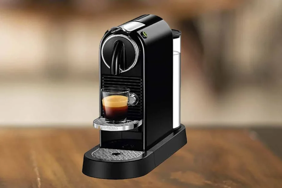 A imagem é composta pela cafeteira de cápsulas Nespresso Citiz de cor preta com uma xícara de café com bebida dentro. A cafeteira está sobre uma mesa de madeira e o restante do fundo está desfocado.