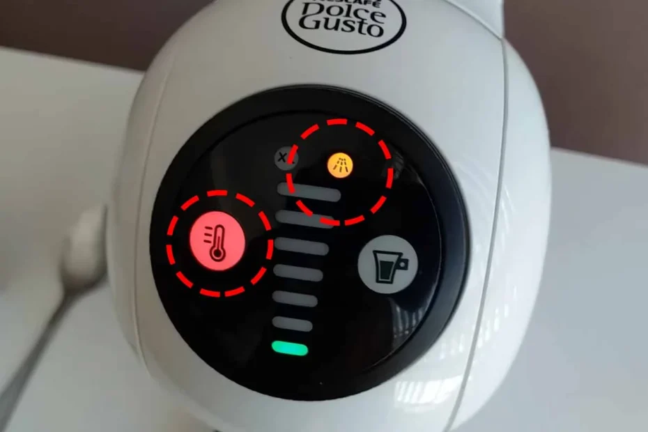 A imagem contém a Dolce Gusto Genio branca com alerta de descalcificação de cor laranja ativado, bem como acesa o botão de temperatura na cor vermelha. Foi destacado essas duas luzes com uma circunferência pontilhada de cor vermelha