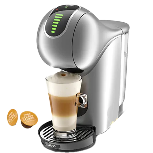 A imagem contém a cafeteira Genio S Touch da Dolce Gusto. A cor predominante dessa cafeteira expresso é prata. Há duas cápsulas ao lado cafeteira. Na cafeteira há um copo de cappucino sendo preparado.